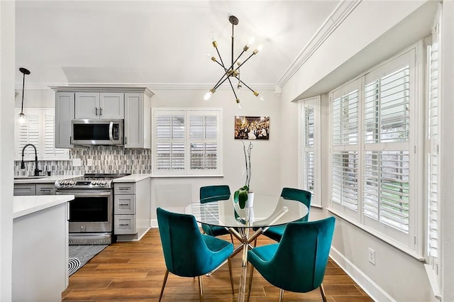 kitchen featuring stainless steel appliances, gray cabinets, light countertops, pendant lighting, and a sink