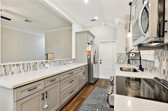 kitchen featuring decorative light fixtures, stainless steel appliances, gray cabinets, light countertops, and a sink