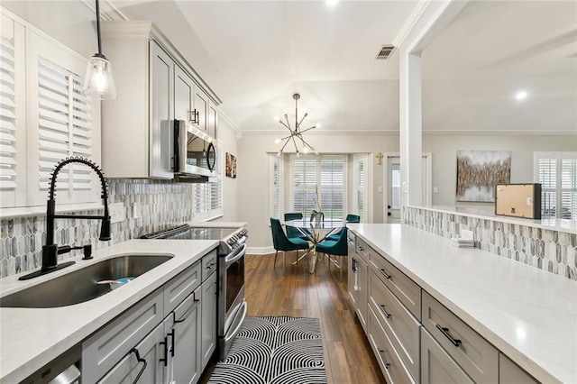 kitchen with appliances with stainless steel finishes, decorative light fixtures, light countertops, gray cabinetry, and a sink