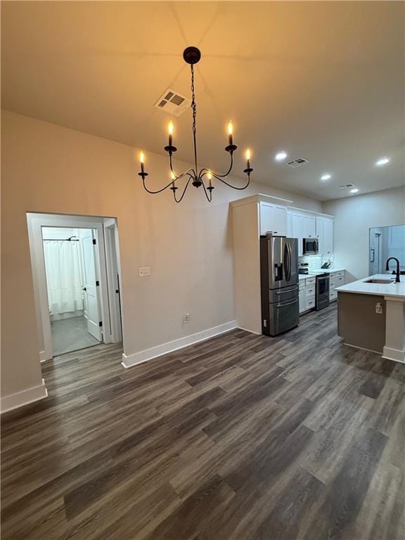 kitchen with stainless steel appliances, light countertops, dark wood-type flooring, and white cabinetry