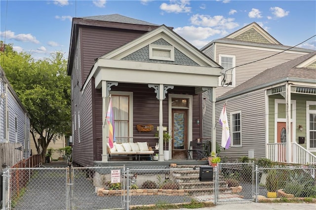 shotgun-style home featuring a fenced front yard, covered porch, and a gate