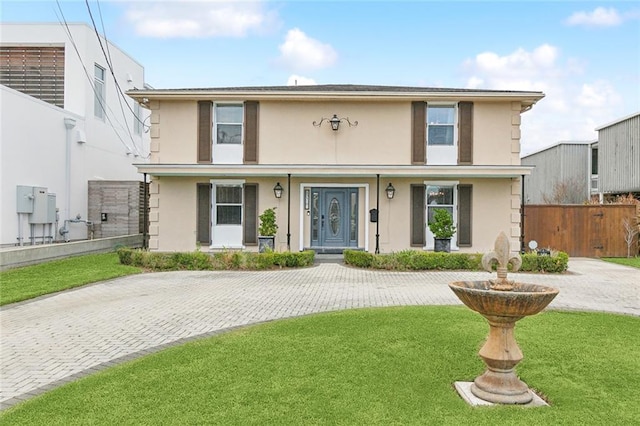 view of front of house with a front yard, covered porch, fence, and stucco siding