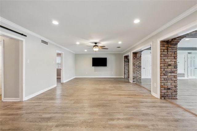 unfurnished living room with light wood-type flooring, a barn door, visible vents, and a ceiling fan