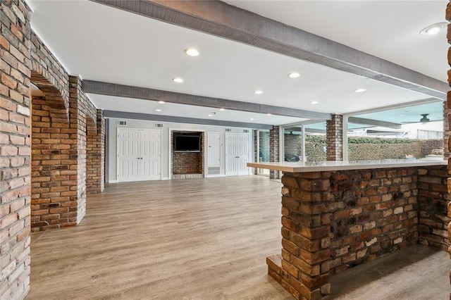 bar featuring beamed ceiling, light wood-style flooring, and brick wall