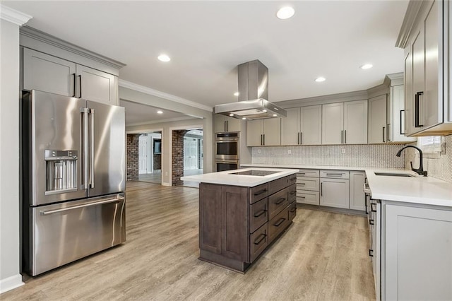 kitchen featuring island range hood, a center island, stainless steel appliances, light countertops, and a sink