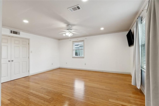 unfurnished bedroom featuring light wood-type flooring, visible vents, crown molding, and baseboards