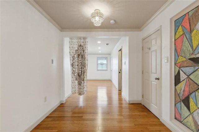 hall featuring baseboards, ornamental molding, an inviting chandelier, and light wood-style floors