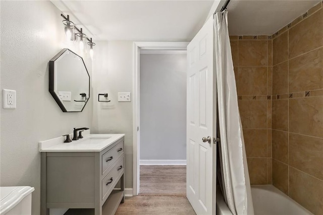 bathroom with shower / tub combo, vanity, baseboards, and wood finished floors