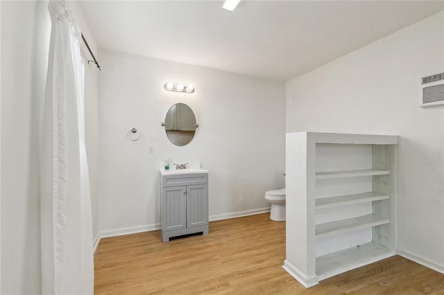 bathroom featuring toilet, baseboards, wood finished floors, and vanity