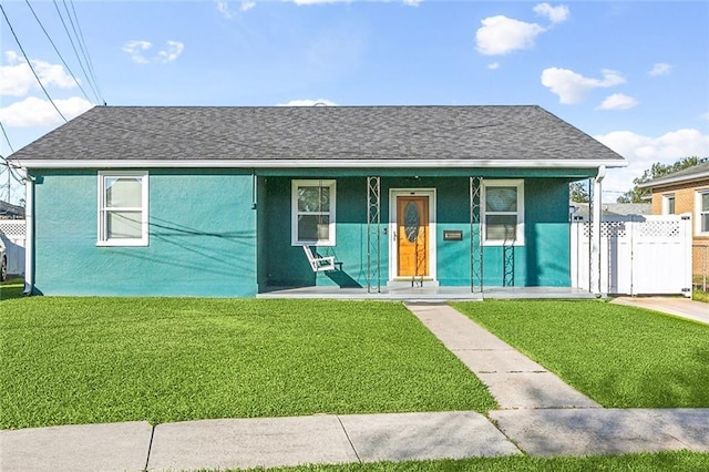 view of front of house featuring covered porch, roof with shingles, a front lawn, and stucco siding