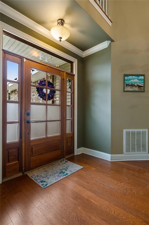 entryway featuring baseboards, wood finished floors, visible vents, and crown molding