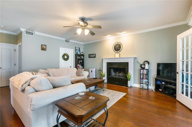 living room with crown molding, a high end fireplace, visible vents, and dark wood finished floors