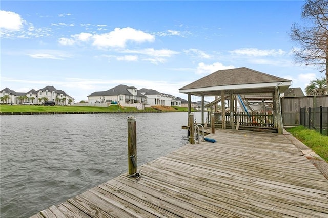 view of dock featuring a residential view, a water view, fence, and boat lift