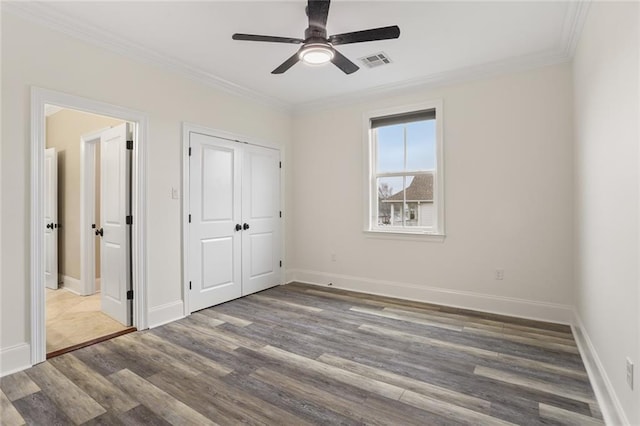 unfurnished bedroom featuring ornamental molding, dark wood-style flooring, visible vents, and baseboards