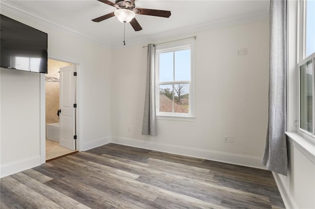 spare room featuring crown molding, dark wood finished floors, and baseboards
