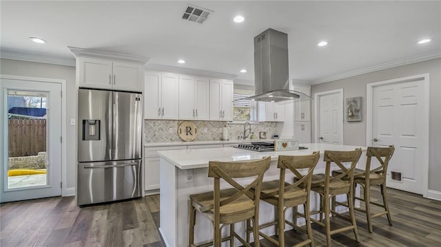 kitchen with island range hood, appliances with stainless steel finishes, a center island, light countertops, and white cabinetry