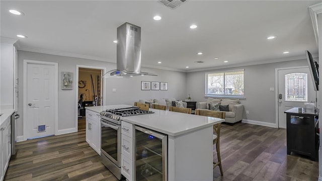 kitchen featuring wine cooler, island range hood, white cabinetry, light countertops, and stainless steel gas range