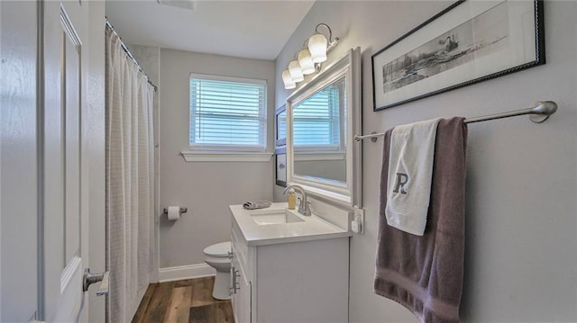 bathroom with a shower with shower curtain, toilet, vanity, wood finished floors, and baseboards