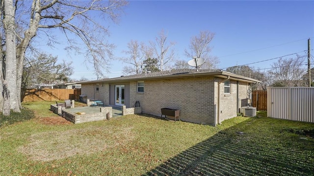 rear view of house with french doors, brick siding, a lawn, a patio area, and fence