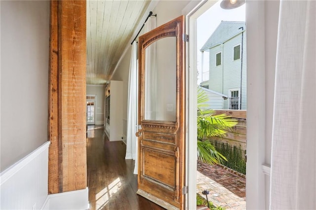 doorway to outside featuring dark wood-style floors, wood ceiling, and a wainscoted wall