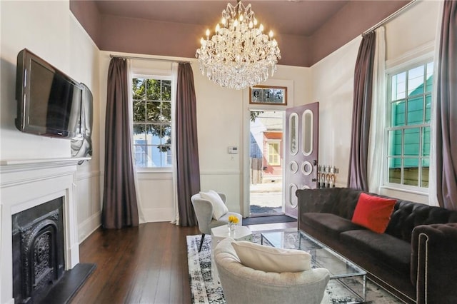 717 Port St, New Orleans, LA 70117 - living area featuring a chandelier, a fireplace with raised hearth, dark wood-style floors, and wainscoting