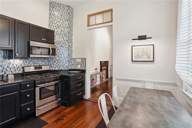 717 Port St, New Orleans, LA 70117 - kitchen with decorative backsplash, dark countertops, stainless steel appliances, and dark wood-type flooring