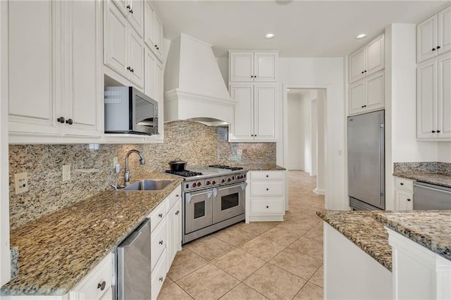 kitchen with white cabinetry, stone countertops, high quality appliances, and custom range hood