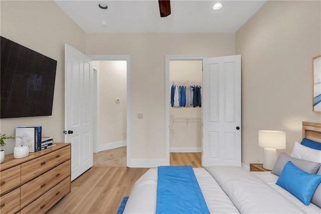 bedroom with recessed lighting, a closet, light wood-style flooring, a spacious closet, and baseboards