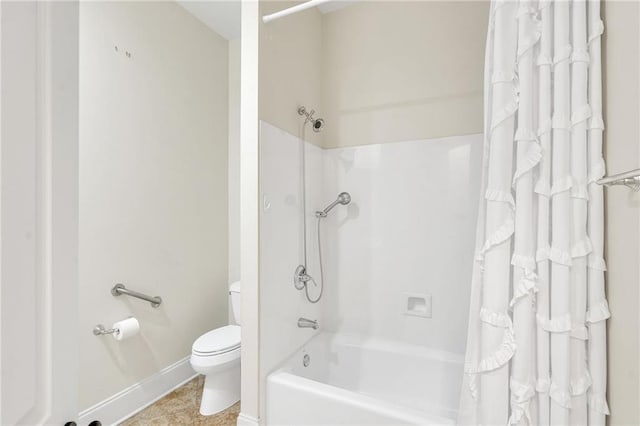 bathroom featuring toilet, shower / tub combo, and baseboards