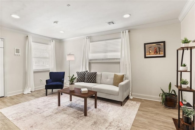 living area with light wood-type flooring, visible vents, and crown molding