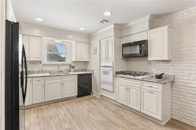 kitchen with visible vents, black appliances, white cabinetry, a sink, and a warming drawer