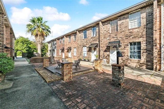 exterior space with brick siding and a patio