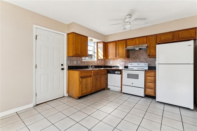 kitchen featuring white appliances, dark countertops, brown cabinets, and under cabinet range hood