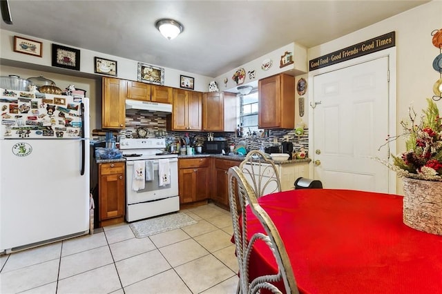 kitchen featuring dark countertops, white appliances, under cabinet range hood, and brown cabinetry