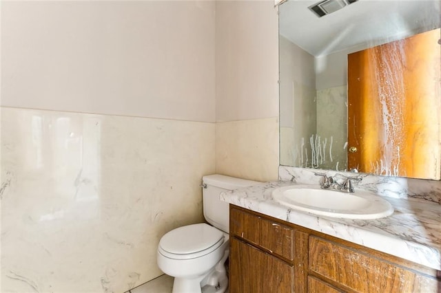 bathroom featuring toilet, vanity, and visible vents