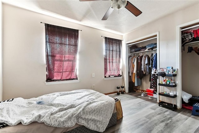 bedroom with light wood-type flooring, ceiling fan, a textured ceiling, and baseboards