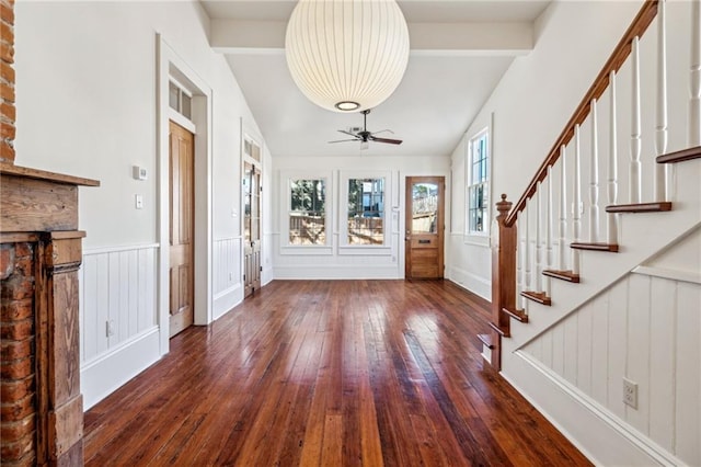 entrance foyer with dark wood finished floors, a wainscoted wall, ceiling fan, vaulted ceiling with beams, and stairs