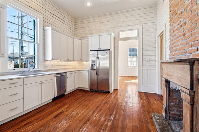 kitchen with dark wood finished floors, stainless steel appliances, light countertops, white cabinets, and a sink