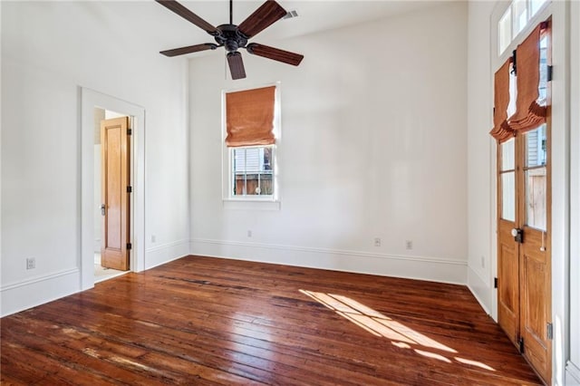 unfurnished room featuring dark wood-style floors, ceiling fan, and baseboards