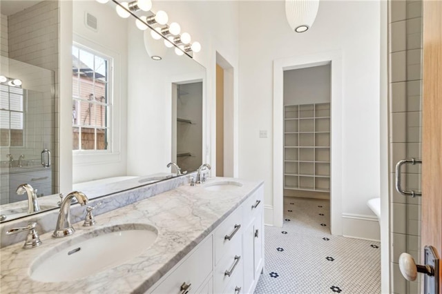 full bathroom featuring a spacious closet, a sink, visible vents, and a shower stall