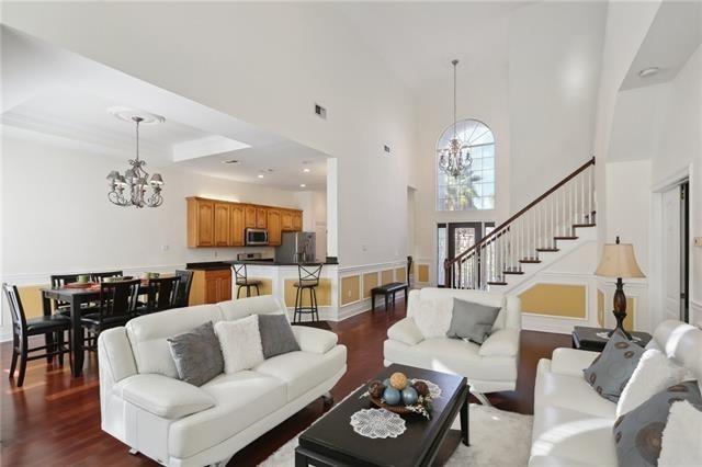 living area with a towering ceiling, stairway, a chandelier, and dark wood-style flooring