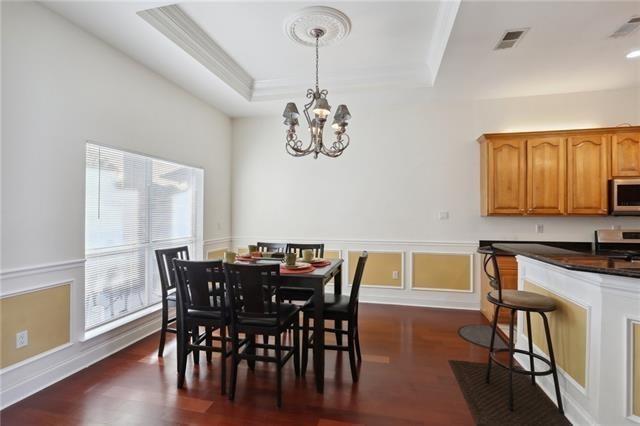 dining area with visible vents, wainscoting, a raised ceiling, dark wood finished floors, and an inviting chandelier