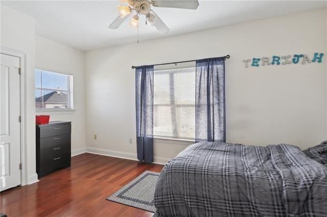 bedroom with dark wood finished floors, baseboards, and ceiling fan