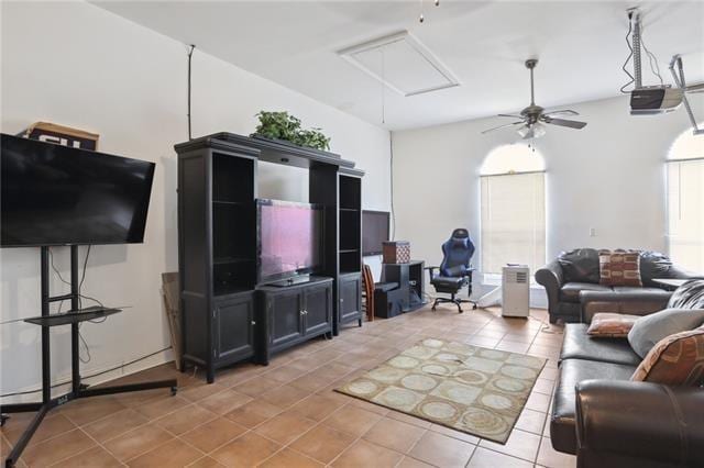 living area featuring attic access, ceiling fan, and light tile patterned floors