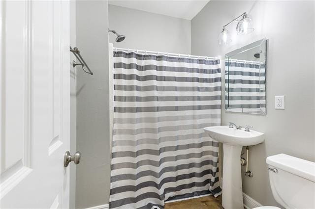 bathroom with a shower with shower curtain, toilet, and a sink