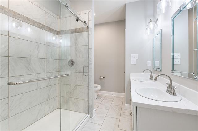 full bathroom featuring a sink, baseboards, toilet, and a shower stall