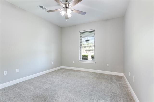carpeted spare room with visible vents, a ceiling fan, and baseboards