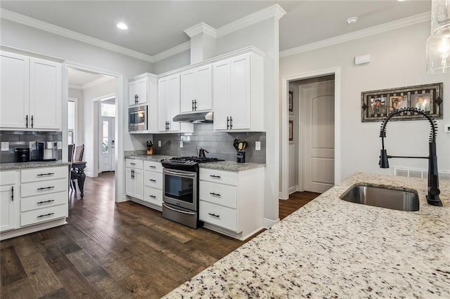 kitchen featuring dark wood-style flooring, stainless steel appliances, under cabinet range hood, white cabinetry, and a sink