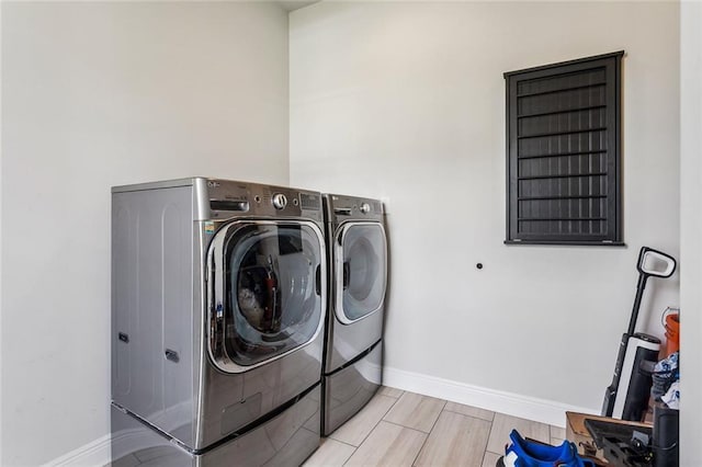 laundry area with light wood-style floors, laundry area, baseboards, and washing machine and clothes dryer