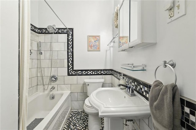 bathroom with toilet, bathing tub / shower combination, a sink, and tile walls